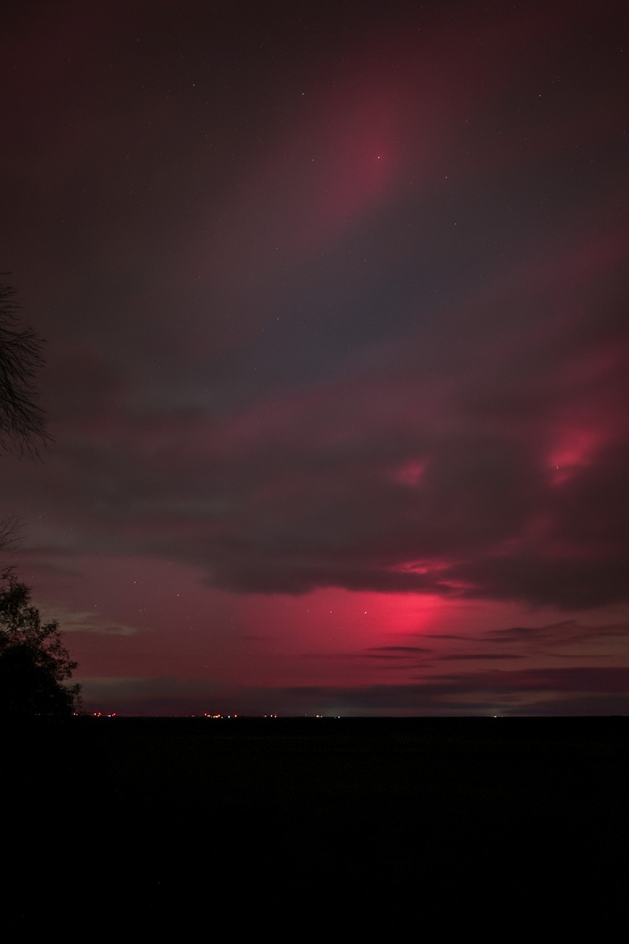 Crimson aurora glow over a darkened horizon at night